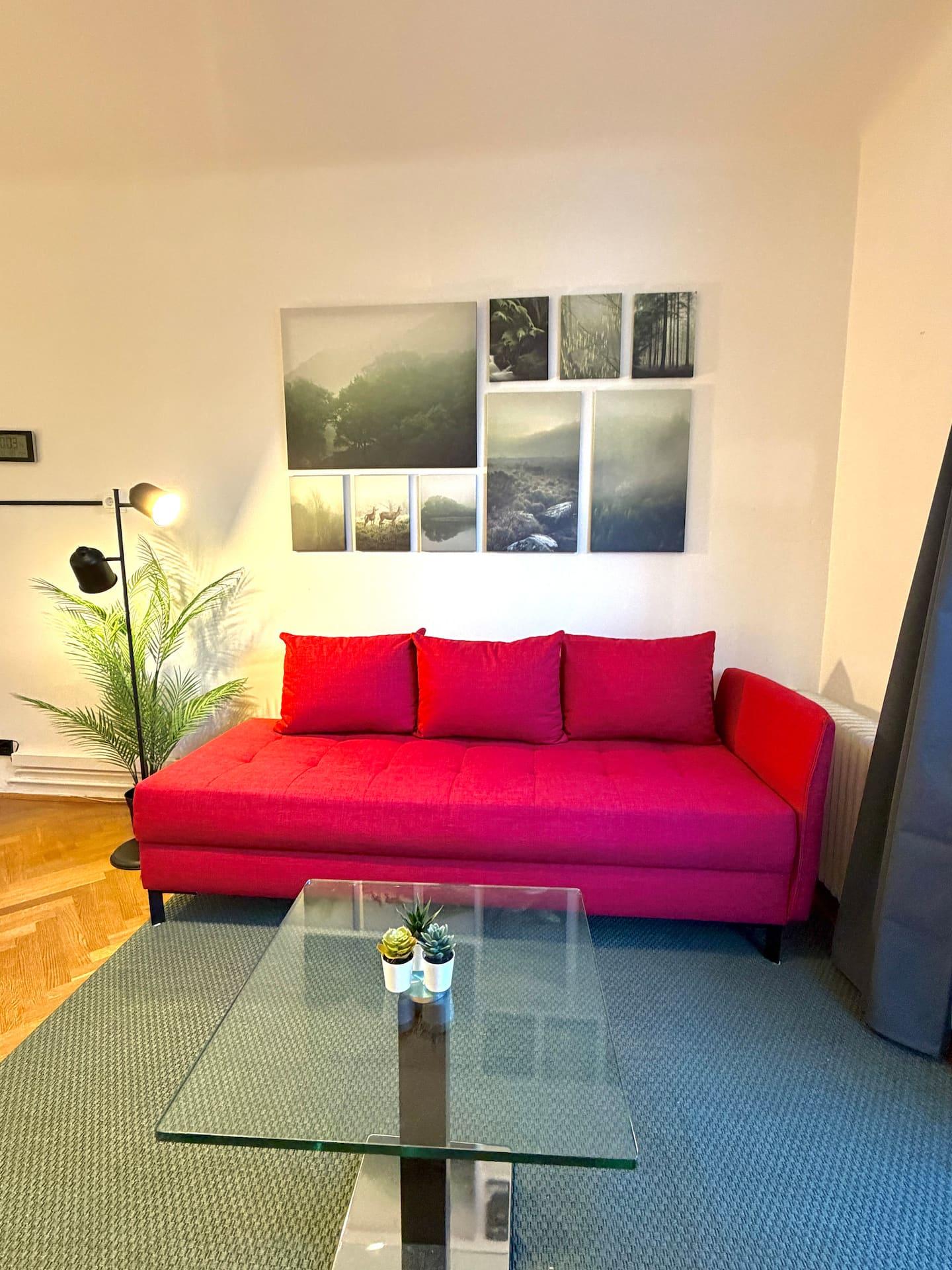 Wohnbereich mit rotem Sofa und Glastisch