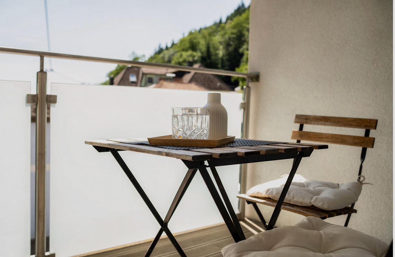 Loggia mit Bistrotisch und Blick auf den bewaldeten Hang