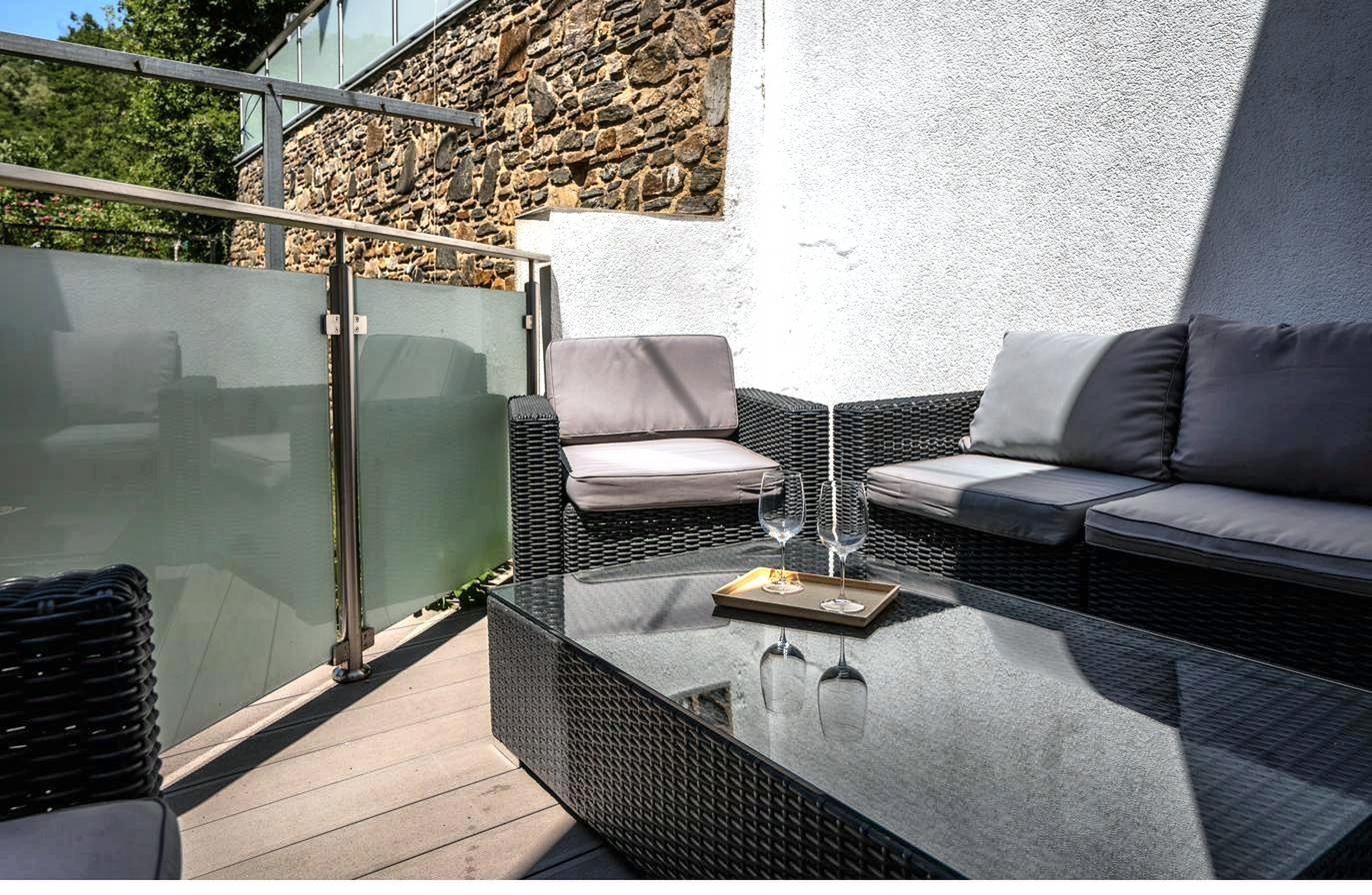 Terrasse mit Rattan-Lounge vor einer Steinmauer
